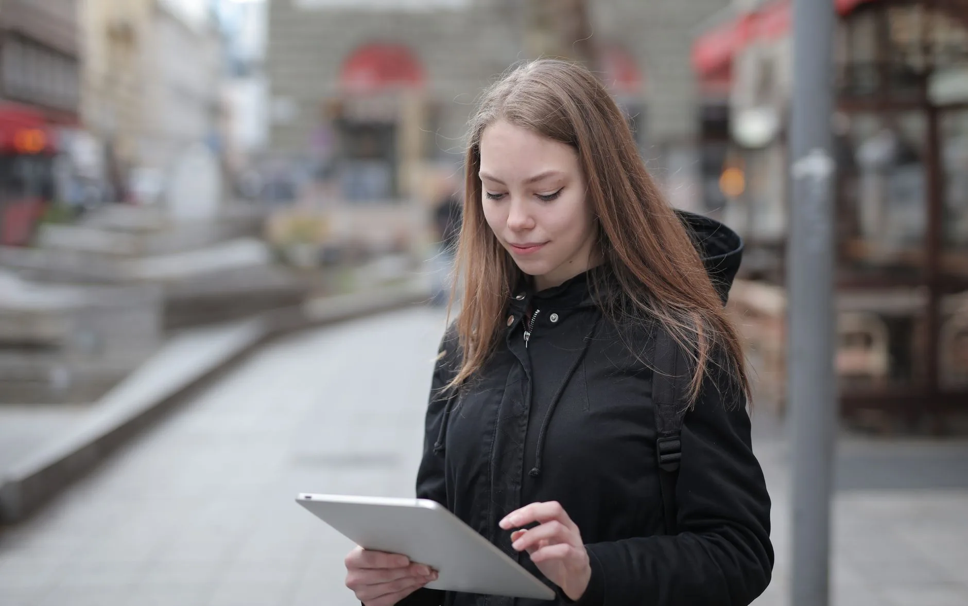 Hand hovers over tablet displaying grid of action symbols, dynamic AAC symbols.